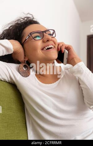 young woman with curly hair talking on the phone in an office Stock Photo