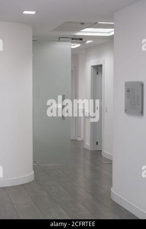 corridor with white walls with glass door, lamps and wooden floor Stock Photo