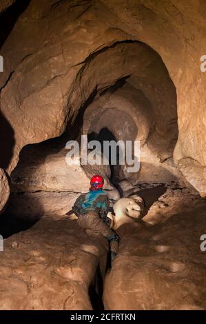 Dominika Wroblewska in the very muddy approach to Moss Chamber in Peak Cavern, looking upslope Stock Photo