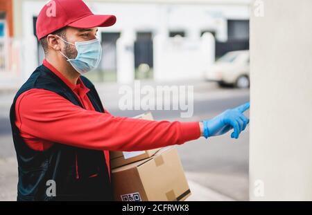 Courier with protective mask and gloves delivering packages at home during coronavirus pandemic time - Covid 19 spread prevention concept Stock Photo