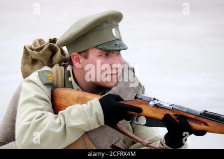 Soldier of the Russian Empire of early 20th century aiming a rifle during the city day of Moscow in Mitino park. Historical reconstruction Stock Photo