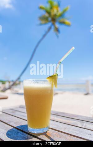Pineapple juice in glass on the tropical beach near sea, close up. Travel and vacation concept Stock Photo