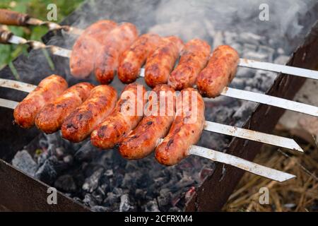 pork sausages strung on skewers cooked on grilled, food cooked outdoors. Stock Photo