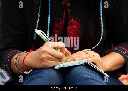 Travelers thai women visit and sitting writing note on the book for memory of detail between journey travel on rowing bamboo rafts on Pang Ung lake in Stock Photo