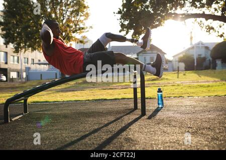 Man with prosthetic leg performing crunches exercise in the park Stock Photo