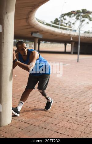Man with prosthetic leg performing stretching exercise in urban park Stock Photo