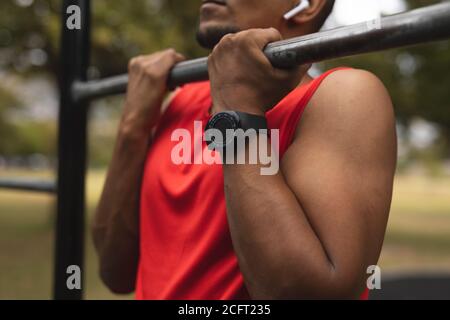 Mid section of man performing pull ups exercise in the park Stock Photo