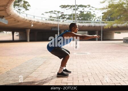 Man with prosthetic leg performing squat exercise in urban park Stock Photo