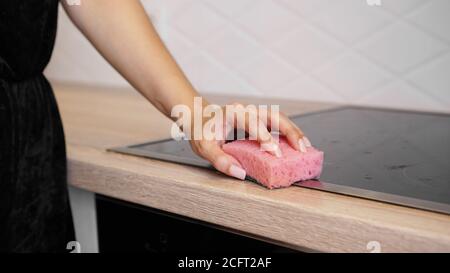 Female hand washing electric hob in the modern kitchen Stock Photo