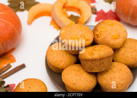 recipe and ingredients for cooking autumn pumpkin cupcakes . top view on a light background. fresh cupcakes on a plate in the middle with pumpkins. Stock Photo