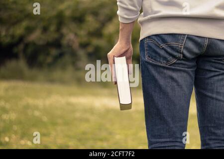 Christian worship and praise. Young man his holding the Holy Bible in his hand.View from behind. Stock Photo