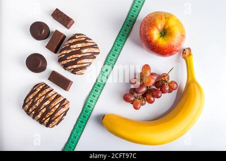 The concept of choosing between diet and unhealthy food. Fruits or sweets.