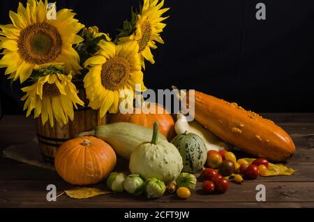 Still life with sunflowers from vegetables on a black background. Thanksgiving and harvest. Stock Photo