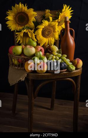 Still life with sunflowers from fruits, grapes and wine on a black background. Thanksgiving and harvest. Stock Photo