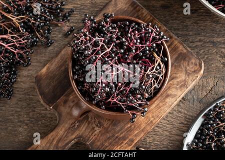 Black elder berries in a brown ceramic pot, top view Stock Photo