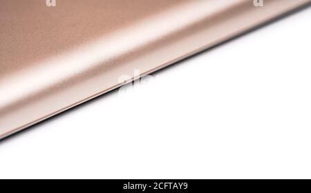 Rose gold colored metal smartphone case, closeup macro detail forming diagonal line with space for text right, abstract technology background Stock Photo