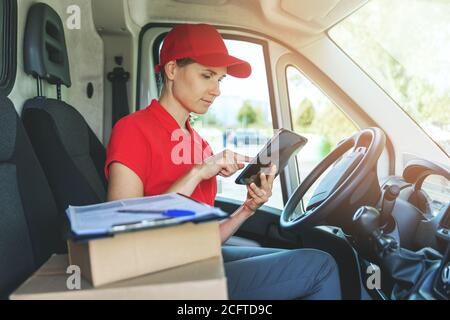 delivery woman using digital tablet while sitting in van Stock Photo