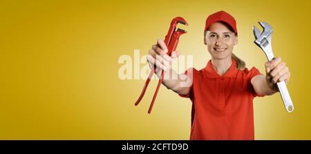 handywoman in red uniform with tools in hands on yellow background with copy space Stock Photo