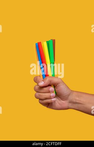Hand holding colored markers on orange background Stock Photo