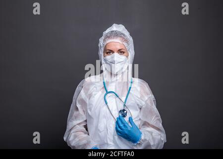 Doctor wearing PPE and working during the covid - 19 pandemic concept. Portrait of young female doctor in a protective mask, gloves, glasses and suit Stock Photo