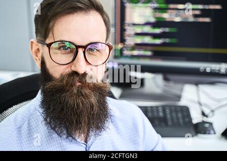 Closeup portrait of a serious computer programmer developer working in IT office, sitting at desk and coding a project in software development company Stock Photo