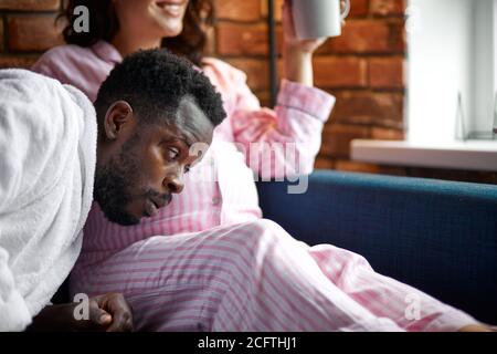 beautiful pregnant woman and her handsome afro husband listening to baby in belly, spending time together at home Stock Photo