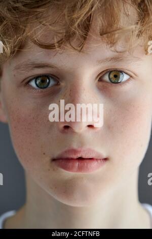 close-up portrait of redhead freckled teenager boy with bewitching look, caucasian boy with green eyes confidently looks at camera Stock Photo