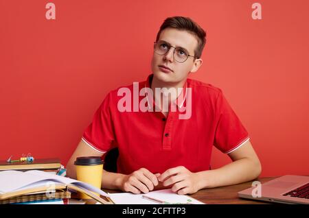 thoughtful caucasian man work with laptop, sit at table isolated, he has too much work, sits in contemplation Stock Photo