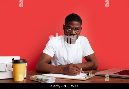 young stressed african male working with computer laptop in frustration, depression. he has stress problems and despair at work, isolated on red backg Stock Photo