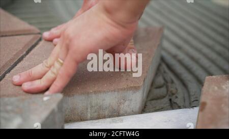 Worker lay tiles on the sidewalk. Laying concrete paving slabs in house courtyard driveway patio. Professional workers bricklayers are installing new Stock Photo