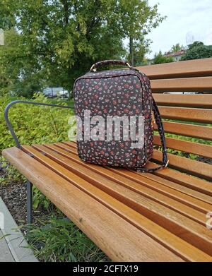 Lost backpack on the bench. The woman lost her backpack on a wooden bench. Stock Photo