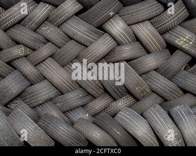 Conceptual photo showing a pile of used car tires arranged in a geometric pattern. Ecology, consumerism, pollution, excess. Stock Photo