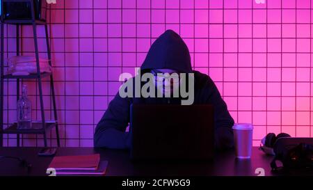 Young male financial hacker at office sitting working on laptop. Stock Photo