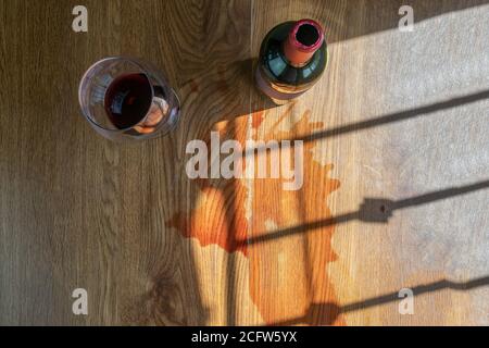 top view of glass and bottle of red wine with spilled wine on the table Stock Photo