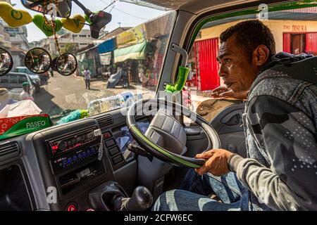 A driver steers a minibus through the streets of Ende, Flores, Indonesia. Stock Photo