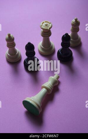 Conceptual image about the fall from power. Some chess pieces watch the fallen king impassively Stock Photo