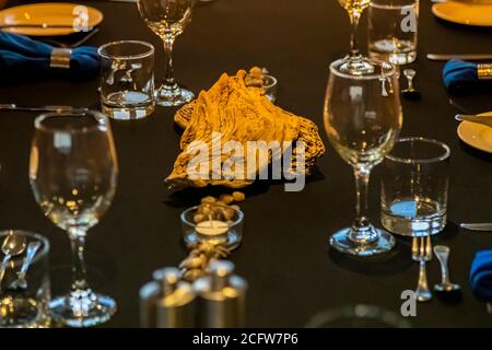 A large shell serves as a table decoration at a festively set dinner table aboard the True North off Alor, Indonesia. Stock Photo