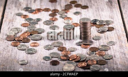 Stacks of quarters on an old wooden table amid scattered coins / investment growth concept Stock Photo