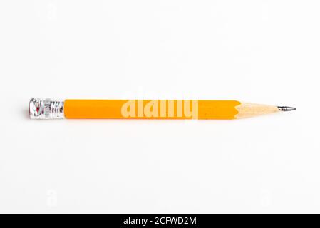 A close-up or macro shot with selective focus of a sharpened classic yellow-orange hexagonal pencil stub set on plain white paper. Stock Photo
