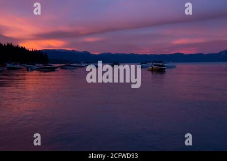 Gorgeous deep late sunset of rose purple, and blue, Lake Tahoe, Tahoe City, boats and mountains in background Stock Photo