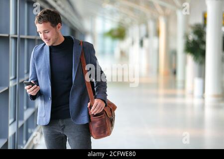 Business man using mobile phone app in airport. Young business professional man texting smartphone walking inside office building or airport terminal Stock Photo