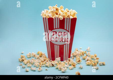 Large paper cup filled with salted Pocorn on bright blue Background Stock Photo