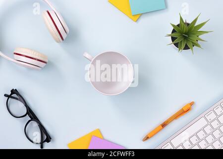 Center Coffee Cup and Office Supplies as Keyboard,Headphone,Pen,Sticky Note,Office Plants,Glasses on Modern Clean Creative Office Desk or Table on Top Stock Photo