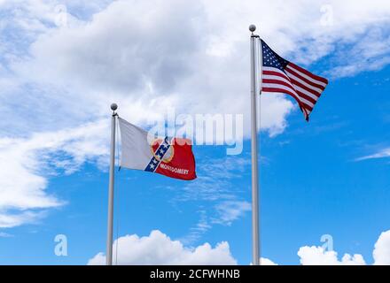 Montgomery, AL / USA - August 27, 2020: City of Montgomery flag and United States of America flag waving against blue sky Stock Photo