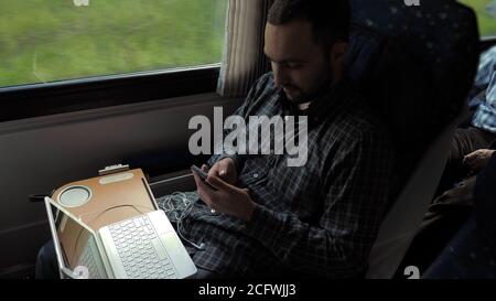 Businessman Commuting To Work On Train Using Mobile Phone. Stock Photo