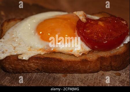 art photo of fried eggs with tomato slices fried in butter on toast close-up Stock Photo
