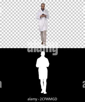 Male arab doctor texting message on the phone while walking, Alpha Channel Stock Photo