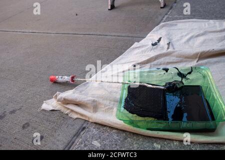 Black paint in a green roller tray outdoors enamel paint with throw down tarp Stock Photo