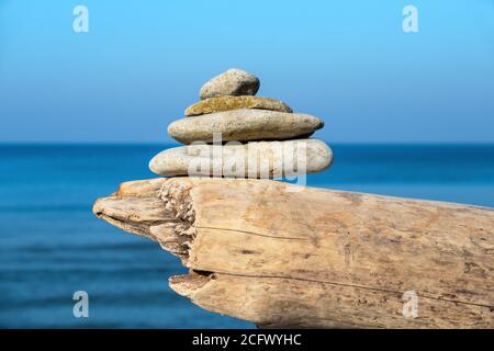 Stack of pebble stones on a log. Toila beach, Estonia Stock Photo