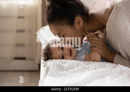 Affectionate african ethnicity mother kissing cheek of little toddler baby.
